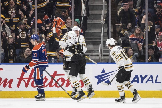 Boston Bruins' Jake DeBrusk (74), Charlie McAvoy (73) and Pavel Zacha (18) celebrate a goal as Edmonton Oilers' Ryan McLeod (71) skates past during overtime an NHL hockey game Wednesday, Feb. 21, 2024, in Edmonton, Alberta. (Jason Franson/The Canadian Press via 番茄直播)