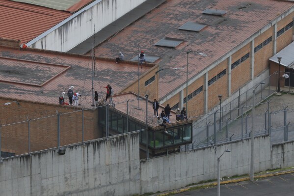 Los presos se encuentran en el techo de la cárcel de Turi, donde decenas de guardias penitenciarios y policías han sido secuestrados por los reclusos, en Cuenca, Ecuador, el jueves 31 de agosto de 2023. En las últimas 24 horas, Ecuador ha sido sacudido por las explosiones. de cuatro coches bomba y la toma de rehenes de más de 50 agentes encargados de hacer cumplir la ley dentro de varios centros de detención. (Foto AP/Xavier Caivinagua)