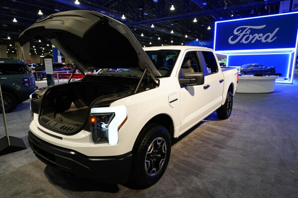 FILE - The Ford F-150 Lightning displayed at the Philadelphia Auto Show, Friday, Jan. 27, 2023, in Philadelphia. With U.S. electric vehicle sales starting to slow, Ford Motor Co. says, Thursday, April 4, 2024, it will delay rolling out new electric pickup trucks and a new large electric SUV as it adds gas-electric hybrids to its model lineup. (AP Photo/Matt Rourke, File)