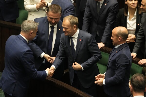 Newly elected Poland's Prime Minister Donald Tusk, center, is congratulated by lawmakers after his government passed a confidence vote at the parliament in Warsaw, Poland, Tuesday Dec. 12, 2023. (AP Photo/Czarek Sokolowski)