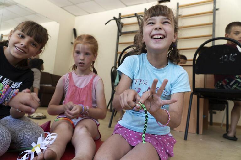 Diana, left, Lena and Sonya, right, from the Donetsk region craft in the playroom at a camp in Zolotaya Kosa, the settlement on the Sea of Azov, Rostov region, southwestern Russia, Friday, July 8, 2022. Russia portrays its adoption of Ukrainian children as an act of generosity that gives new homes and medical resources to helpless minors. (AP Photo)