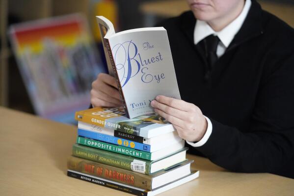 FILE - Amanda Darrow, director of youth, family and education programs at the Utah Pride Center, poses with books, including "The Bluest Eye," by Toni Morrison, that have been the subject of complaints from parents, on Dec. 16, 2021, in Salt Lake City. Publisher Penguin Random House and PEN America sued a Florida school district Wednesday, May 17, 2023, over its removal of books about race and LGBTQ+ identities, the latest opposition to a policy central to Gov. Ron DeSantis’ agenda as he prepares to run for president. Among the removed books are “The Bluest Eye” by Toni Morrison, “The Perks of Being a Wallflower” by Stephen Chbosky, “The Nowhere Girls” by Amy Reed and “Lucky” by Alice Sebold. (AP Photo/Rick Bowmer, File)