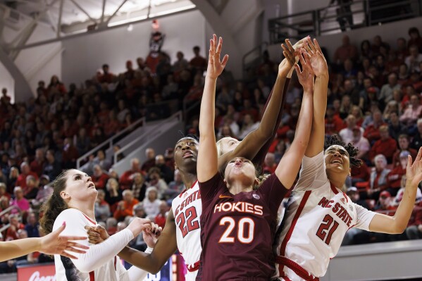 Virginia Tech's Olivia Summiel (20) and North Carolina State's Madison Hayes (21), North Saniya Rivers (22), and River Baldwin (1) vie for a rebound during the first half of an NCAA college basketball game in Raleigh, N.C., Thursday, Feb. 8, 2024. (AP Photo/Ben McKeown)