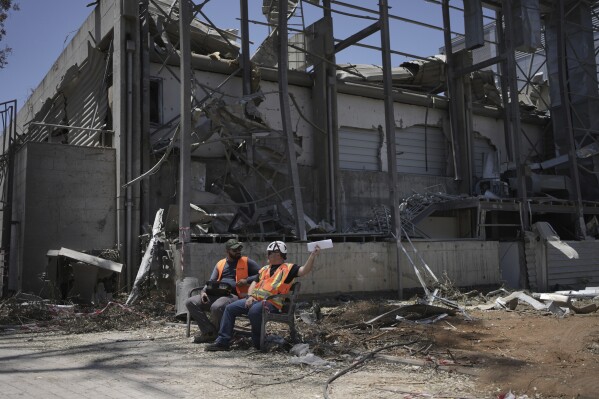 Workers sit next to a building at the Weizmann Institute of Science destroyed by an Iranian missile in Rehovot, Thursday, June 19, 2025. (AP Photo/Maya Alleruzzo)