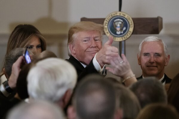 
              President Donald Trump, joined by Vice President Mike Pence, right, and first lady Melania Trump, left, gives the thumbs-up as he greets people during the Congressional Ball in the G...