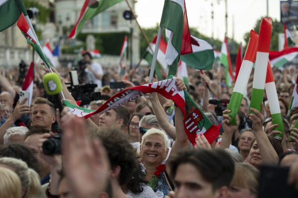 People wave Hungarian national flags next to the Danube river, in Budapest, Thursday May 30, 2024, where politicians took to the debate stage ahead of the European Parliament elections. The debate, where the leaders of 11 party lists running in the June 9 elections, is the first to be broadcast by Hungary's public media since 2006, while protesters outside demonstrated against the public broadcaster that is hosting the event. (AP Photo/Denes Erdos)