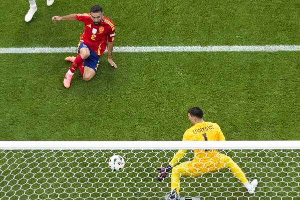 Spain's Dani Carvajal, left, scores his side's third goal against Croatia's goalkeeper Dominik Livakovicduring a Group B match between Spain and Croatia at the Euro 2024 soccer tournament in Berlin, Germany, Saturday, June 15, 2024. (AP Photo/Petr Josek)