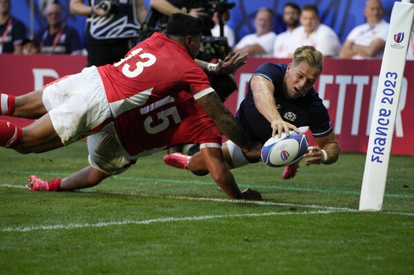 Scotland's Duhan van der Merwe, right, Tonga's Malakai Fekitoa, left, and Salesi Piutau fight for the ball during the Rugby World Cup Pool B match between Scotland and Tonga at the Stade de Nice, in Nice, France, Sunday, Sept. 24, 2023. (AP Photo/Daniel Cole)