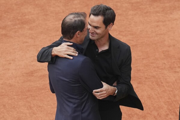 Rafa Nadal, a la izquierda, abraza a Roger Federer durante una ceremonia de despedida en la cancha central Philippe-Chatrier del estadio Roland-Garros de París, el domingo 25 de mayo de 2025. (Foto AP/Christophe Ena)