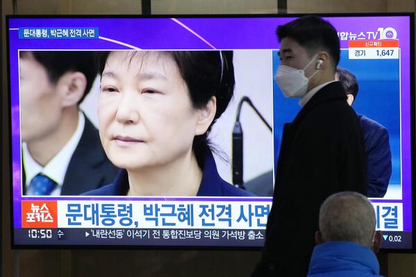 A man passes by a TV screen showing a file image of former South Korean President Park Geun-hye during a news program at the Seoul Railway Station in Seoul, South Korea, Friday, Dec. 24, 2021. The South Korean government said Friday it will grant a special pardon to Park, who is serving a lengthy prison term for bribery and other crimes. The Korean letters read "President Moon Jae-in pardons Park Geun-hye." (AP Photo/Ahn Young-joon)