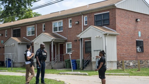 Resident Ashley Johnson speaks with Baltimore Police officers about the mass shooting incident in the Southern District of Baltimore, Monday, July 3, 2023. Police say a number of people were killed and dozens of others were wounded in a shooting that took place during a block party just after midnight on Sunday. (AP Photo/Nathan Howard)
