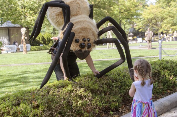 This image released by the Bronx Zoo shows a man dressed in a spider costume during the Boo at the Zoo event at the Bronx Zoo in New York on Oct. 2, 2020. Botanical gardens and zoos across the country have become go-to destinations for Halloween. They aim to be fun, while also inspiring kids to learn about nature. (Julie Larsen Maher/Bronx Zoo via AP)