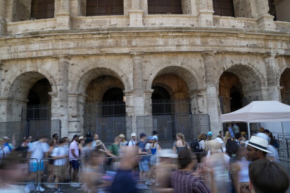 Visitors stand in a line to enter the ancient Colosseum, in Rome, Tuesday, June 27, 2023. Italy's culture and tourism ministers Gennaro Sangiuliano vowed to find and punish a tourist who was filmed carving his name and his girlfriend's name in the wall of the Colosseum, a crime that in the past has resulted in hefty fines. Video of the incident went viral on social media, at a time when Romans have already been complaining about hordes of tourists returning to peak season travel this year. (AP Photo/Andrew Medichini)