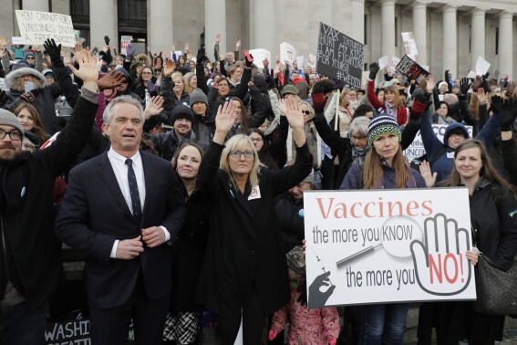 FILE - Robert Kennedy Jr., left, stands at a rally held in opposition to a proposed bill that would remove parents' ability to claim a philosophical exemption to opt their school-age children out of the combined measles, mumps and rubella vaccine, Friday, Feb. 8, 2019, at the Capitol in Olympia, Wash. Rising to prominence during the COVID-19 pandemic due to his strident opposition to vaccines, now Democratic presidential candidate Kennedy Jr. portrays himself as a true Democrat inheriting the mantle of the Kennedy family. (AP Photo/Ted S. Warren, File)