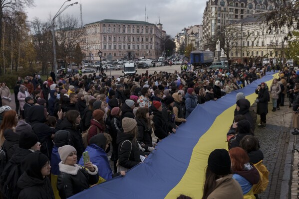 People hold a giant Ukrainian national flag near the St. Michael's Golden-Domed Monastery during a demonstration in central Kyiv, Ukraine, Saturday, Nov. 18, 2023. People gathered to protest against corruption and demand the reallocation of public funds to the Armed Forces. (AP Photo/Alex Babenko)