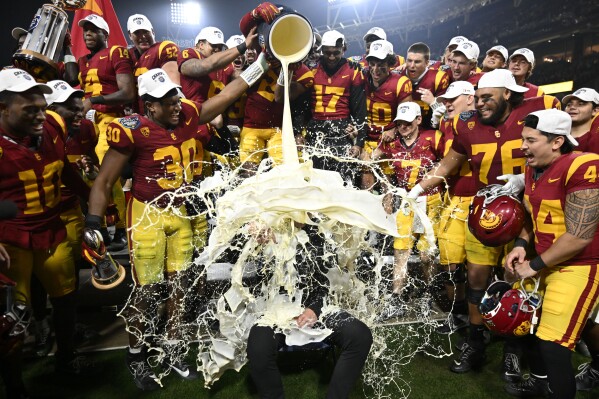 FILE - Southern California coach Lincoln Riley has eggnog poured onto him after USC defeated Louisville in the Holiday Bowl NCAA college football game, Wednesday, Dec. 27, 2023, in San Diego. With the expanded College Football Playoff locked in through 2031, questions still remain about what the rest of the postseason will look like. One thing is certain, there will still be bowl games. (AP Photo/Denis Poroy, File)