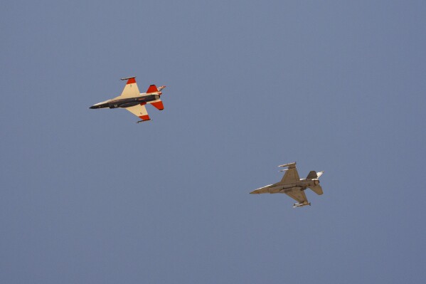 An AI-enabled Air Force F-16 fighter jet, left, flies next to an adversary F-16, as both aircraft race within 1,000 feet of each other, trying to force their opponent into vulnerable positions, on Thursday, May 2, 2024, above Edwards Air Force Base, Calif. The flight is serving as a public statement of confidence in the future role of AI in air combat. The military is planning to use the technology to operate an unmanned fleet of 1,000 aircraft. (AP Photo/Damian Dovarganes)
