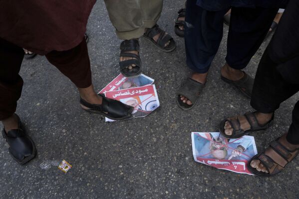 Supporters of the Pakistan Murkazi Muslim League party stand over the crossed posters of Indian Prime Minister Narendra Modi and Indian Minister of Home Affairs Amir Shah during a demonstration against the suspension of water-sharing treaty by India with Pakistan, in Karachi, Pakistan Thursday, April 24, 2025. (AP Photo/Fareed Khan)