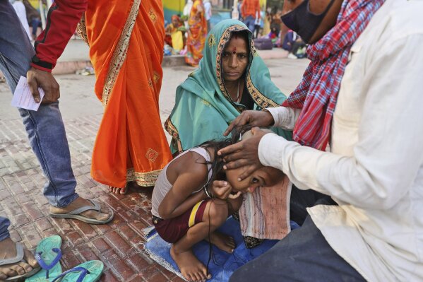 A family get their son head tonsured during Kumbh mela, in Haridwar in the Indian state of Uttarakhand, Monday, April 12, 2021. As states across India are declaring some version of a lockdown to battle rising Covid cases as part of a nationwide second-wave, thousands of pilgrims are gathering on the banks of the river Ganga for the Hindu festival Kumbh Mela. The faithful believe that a dip in the waters of the Ganga will absolve them of their sins and deliver them from the cycle of birth and death. (AP Photo/Karma Sonam)