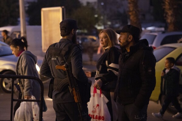 Police officers from Idlib stand in front of a police station in the Bab Touma neighborhood of the Old City of Damascus, Syria, Saturday, Dec. 14, 2024. (AP Photo/Leo Correa)