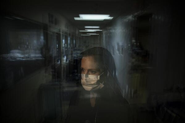 In this photo created with an in-camera multiple exposure, registered nurse Lisa Lampkin, part of a group of nurses who had been treating coronavirus patients in an intensive care unit, stands for a photo in the empty COVID-19 ICU at Providence Mission Hospital in Mission Viejo, Calif., Tuesday, April 6, 2021. "I would go home, try to sleep," she says. Then she would "wake up to the reality of this pandemic again." (AP Photo/Jae C. Hong)