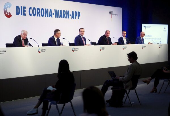 Federal Health Minister Jens Spahn, center, speaks at the presentation of the official Corona Warning App in Berlin, Tuesday, June 16, 2020. Germany has launched a coronavirus tracing app that officials say is so secure even government ministers can use it. Smartphone apps have been touted as a high-tech tool in the effort to track down potential COVID-19 infections. But governments in privacy-conscious Europe have run into legal and cultural hurdles trying to reconcile the need for effective tracing with the continent’s strict data privacy standards. (Hannibal Hanschke/Pool Photo via AP)