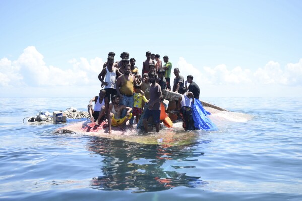 Rohingya refugees stand on their capsized boat before being rescued in the waters off West Aceh, Indonesia, Thursday, March 21, 2024. The wooden boat carrying dozens of Rohingya Muslims capsized off Indonesia's northernmost coast on Wednesday, according to local fishermen. (AP Photo/Reza Saifullah)