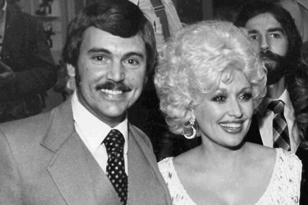 In this undated photo, Nashville, Tenn., newsman Joe Edwards, who has been writing the "Nashville Sound" column for nine years and knows everyone in the country music industry, poses with friend, actor and singer Dolly Parton at an awards reception. Edwards, who chronicled Tennessee news for more than 40 years as a newsman for The Associated Press and helped "Rocky Top" become a state song, died Friday, Feb. 3, 2023. He was 75. (AP Photo/Mark Humphrey)