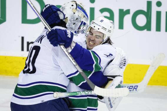 Vancouver Canucks goalie Spencer Martin, left, and forward Conor Garland celebrate defeating the Calgary Flames in a shootout during an NHL hockey game in Calgary, Alberta, Wednesday, Dec. 14, 2022. (Jeff McIntosh/The Canadian Press via AP)