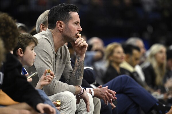 Former Orlando Magic guard JJ Redick, center, watches from a court side seat during the first half of an NBA basketball game, Feb. 14, 2024, in Orlando, Fla. Redick is being hired as the head coach of the Los Angeles Lakers, a person with knowledge of the decision tells The Associated Press. (AP Photo/Phelan M. Ebenhack, file)