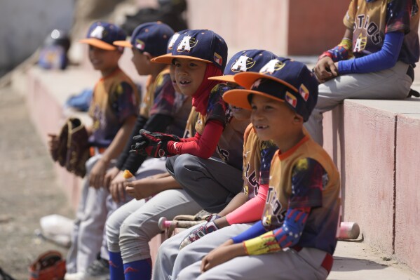 Players of the Astros wait for the start their baseball game against the Cachorros, both teams all Venezuelan, in a public field in the San Juan de Lurigancho area, on the outskirts of Lima, Peru, Saturday, May 11, 2024. Immigrants, mainly Venezuelans, have opened five baseball academies in Peru's capital. (AP Photo/Martin Mejia)