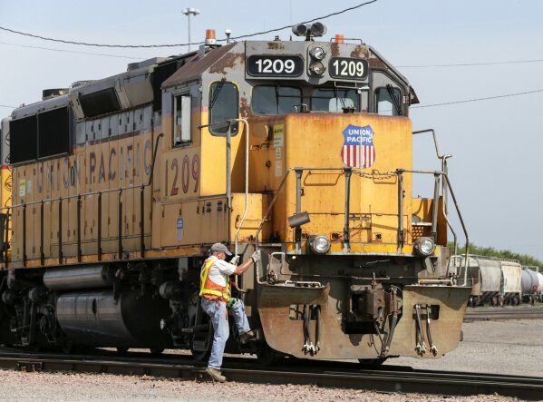 FILE - In this July 20, 2017, file photo, a Union Pacific employee climbs on board a locomotive in a rail yard in Council Bluffs, Iowa. This year’s scheduled completion of a $15 billion automatic railroad braking system will bolster the industry’s argument for eliminating one of the two crew members in most locomotives. But labor groups argue that single-person crews would make trains more accident prone. (AP Photo/Nati Harnik, File)
