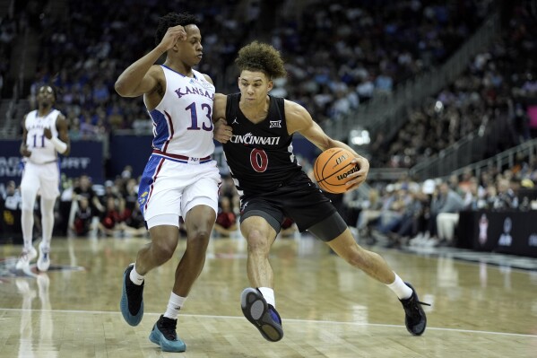 Cincinnati guard Dan Skillings Jr. (0) drives under pressure from Kansas guard Elmarko Jackson (13) during the first half of an NCAA college basketball game Wednesday, March 13, 2024, in Kansas City, Mo. (AP Photo/Charlie Riedel)