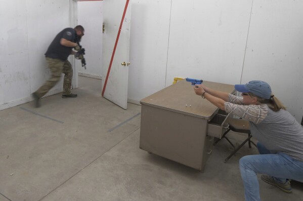 FILE - Christy Belt, Timpanogos Academy fifth-grade teacher, engages in an exercise designed to help teachers make good decisions in critical, high-stress situations such as an active shooter incident during the teacher's academy training at the Utah County Sheriff's Office shooting range, June 29, 2019, in Spanish Fork Canyon, Utah. Utah gun control advocates gathered Monday, March 4, 2024, at the state Capitol in Salt Lake City to urge Republican Gov. Spencer Cox to veto a bill providing free tactical training to Utah teachers who want to bring guns to campus. (AP Photo/Rick Bowmer, File)