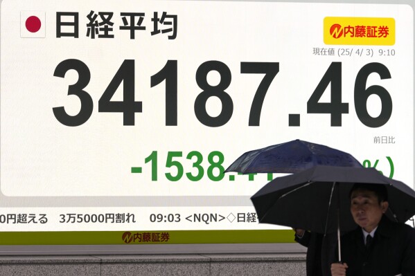 People walk past an electronic stock board showing the day's early loss of Japan's Nikkei 225 index at a securities firm Thursday, April 3, 2025 in Tokyo.(AP Photo/Shuji Kajiyama)