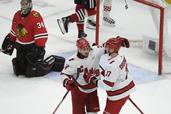 Carolina Hurricanes' Seth Jarvis (24) celebrates with teammate Andrei Svechnikov (37) after scoring against Chicago Blackhawks goalie Petr Mrazek (34) during the third period of an NHL hockey game Sunday, April 14, 2024, in Chicago. (AP Photo/Paul Beaty)