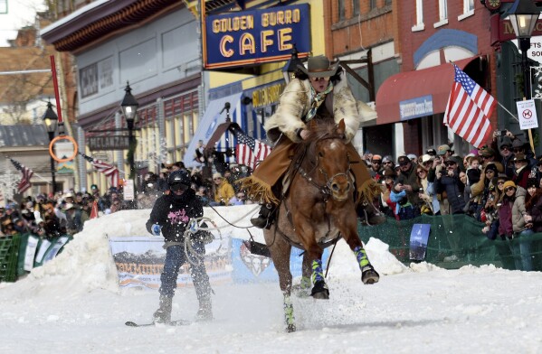 A skijoring team competes in Leadville, Colo., on Saturday, March 2, 2024. Skijoring draws its name from the Norwegian word skikjoring, meaning "ski driving." It started as a practical mode of transportation in Scandinavia and became popular in the Alps around 1900. Today's sport features horses at full gallop towing skiers by rope over jumps and around obstacles as they try to lance suspended hoops with a baton, typically a ski pole that's cut in half. (AP Photo/Thomas Peipert)