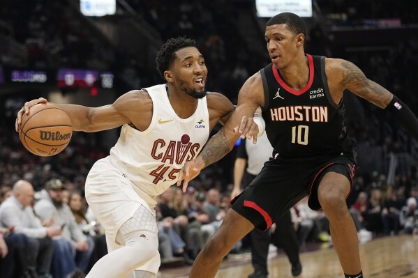 Cleveland Cavaliers guard Donovan Mitchell (45) drives around Houston Rockets forward Jabari Smith Jr. (10) in the first half of an NBA basketball game, Monday, Dec. 18, 2023, in Cleveland. (AP Photo/Sue Ogrocki)