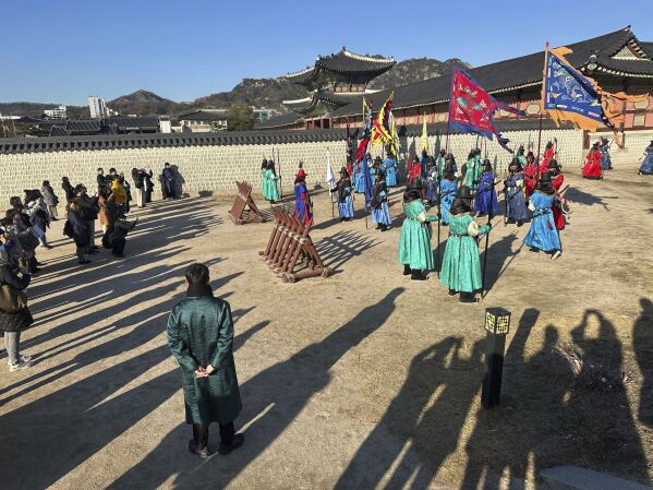 Tourists watch the rehearsal for the royal guard changing ceremony at the Gyeongbokgung Palace, in Seoul, Wednesday, Dec. 4, 2024. (AP Photo/ Jennifer McDermott)