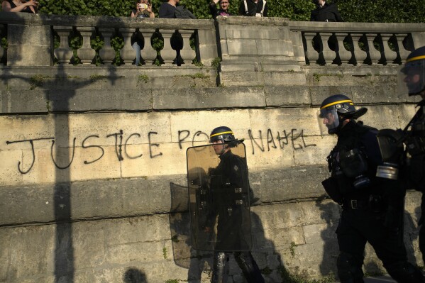 FILE - Police patrol past a graffiti reading 