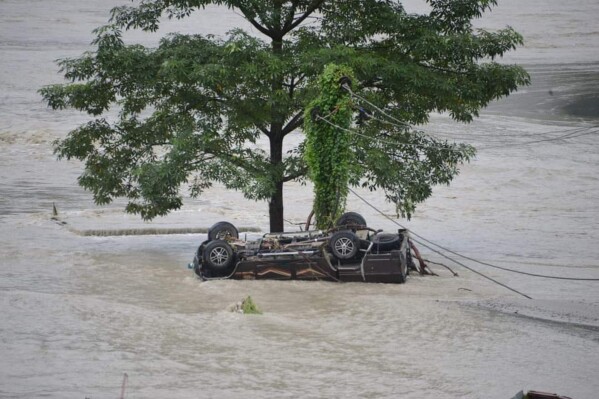 A vehicle that got washed away lies beneath a tree after flash floods triggered by a sudden heavy rainfall swamped the Rangpo town in Sikkim, India, Thursday, Oct.5. 2023. The flooding took place along the Teesta River in the Lachen Valley of the north-eastern state, and was worsened when parts of a dam were washed away. (AP Photo/Prakash Adhikari)