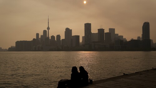 People watch the sunset as the smoke from wildfires drifts into Toronto on Wednesday, June 28, 2023. (Chris Young/The Canadian Press via AP)