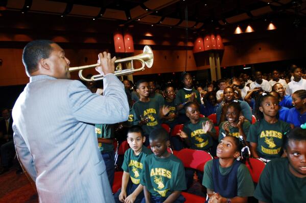 FILE - Jazz trumpeter Wynton Marsalis performs for school children during a program "Cookin' with Jazz'' with celebrity chef Emeril Lagasse in New Orleans, Aug. 28, 2006. During Carnival season, flocks of marching bands parade through the city streets even though jazz music and dancing has been banned in New Orleans public schools for almost a century. The Times-Picayune/The New Orleans Advocate reports the Orleans Parish School Board is poised this week to reverse that policy 100 years after it was passed. School officials say they're glad the local jazz ban has been ignored for decades. The board planned to vote to reverse the policy Thursday, March 24, 2022. (AP Photo/Cheryl Gerber)