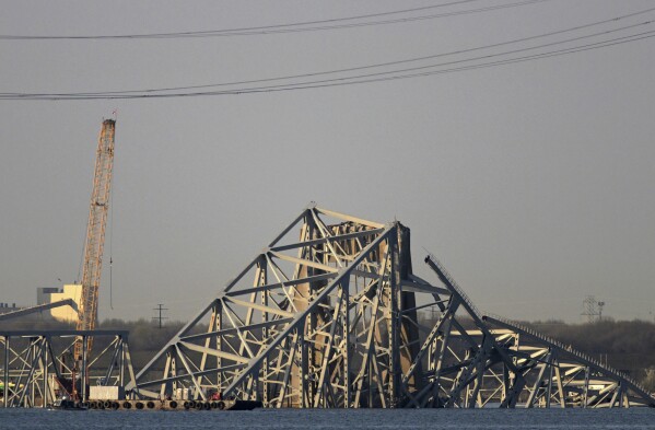 A crane is seen near the wreckage of the Francis Scott Key Bridge on Friday, March 29, 2024 in Baltimore. A cargo ship rammed into the major bridge in Baltimore early Tuesday, causing it to collapse in a matter of seconds. (AP Photo/Steve Ruark)
