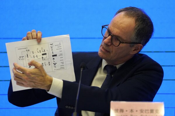Peter Ben Embarek, of the World Health Organization team holds up a chart showing pathways of transmission of the virus during a joint press conference held at the end of the WHO mission in Wuhan, China, Tuesday, Feb. 9, 2021. (AP Photo/Ng Han Guan)