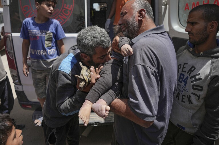 Palestinians hold the body of a dead baby rescued from the rubble of a building destroyed in an Israeli airstrike in Nuseirat, Gaza Strip, Tuesday, May 14, 2024. (AP Photo/Abdel Kareem Hana)