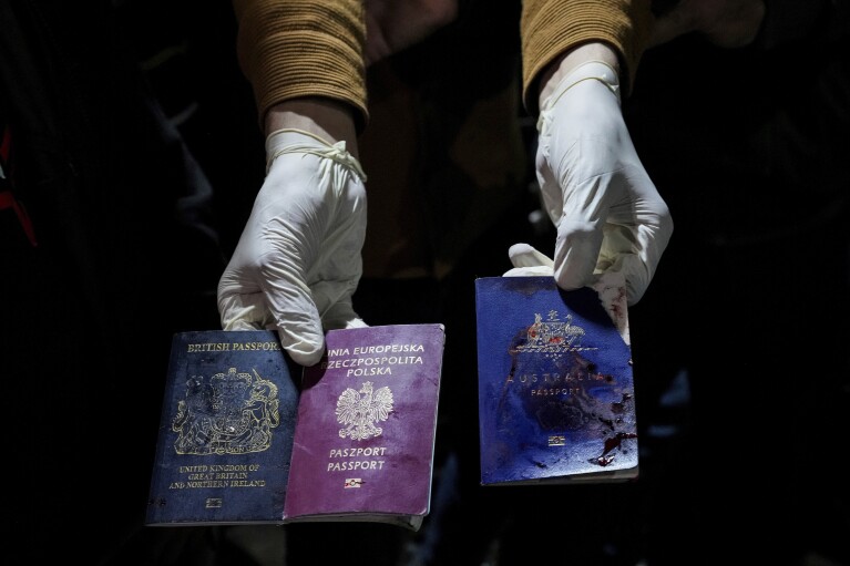 A man displays blood-stained British, Polish, and Australian passports after an Israeli airstrike, in Deir al-Balah, Gaza Strip, Monday, April 1, 2024. (AP Photo/Abdel Kareem Hana)