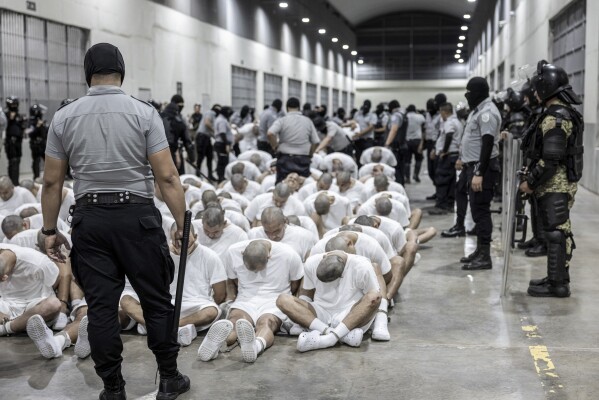 En esta fotografía proporcionada por la oficina de prensa de la presidencia de El Salvador, un guardia penitenciario traslada a deportados de Estados Unidos, presuntos pandilleros venezolanos, al Centro de Reclusión Antiterrorista en Tecoluca, El Salvador, el 16 de marzo de 2025. (Oficina de prensa de la presidencia de El Salvador vía AP, Archivo)