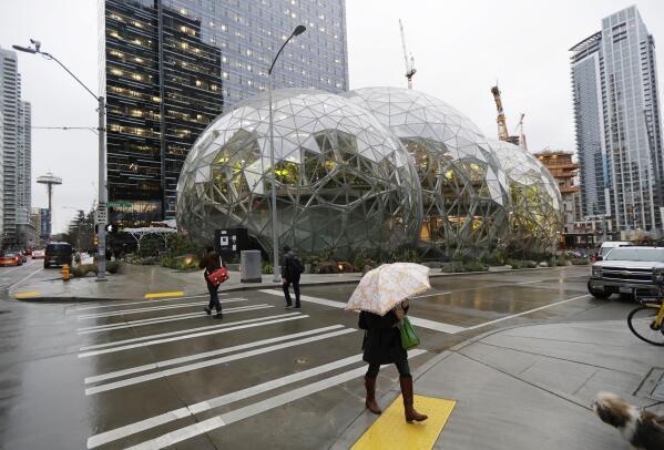 Pedestrians walk past the Amazon Spheres in downtown Seattle on the day of the grand opening of the geodesic domes, which will primarily serve as a working and gathering space for Amazon.com employees, Monday, Jan. 29, 2018, in Seattle. (AP Photo/Ted S. Warren)