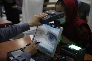 FILE - In this June 30, 2021, file photo an employee scans the eyes of a woman for biometric data needed to apply for a passport, at the passport office in Kabul, Afghanistan. Over two decades, the United States and its allies spent hundreds of millions of dollars building databases for the Afghan people. The nobly stated goal was to promote law and order and government accountability, and to modernize a war-ravaged land.  But in the Taliban’s lightning seizure of power, most of that digital apparatus fell into the hands of an unreliable rulers. Built with few data-protection safeguards, it risks becoming the high-tech jackboots of a surveillance state. (AP Photo/Rahmat Gul, File)